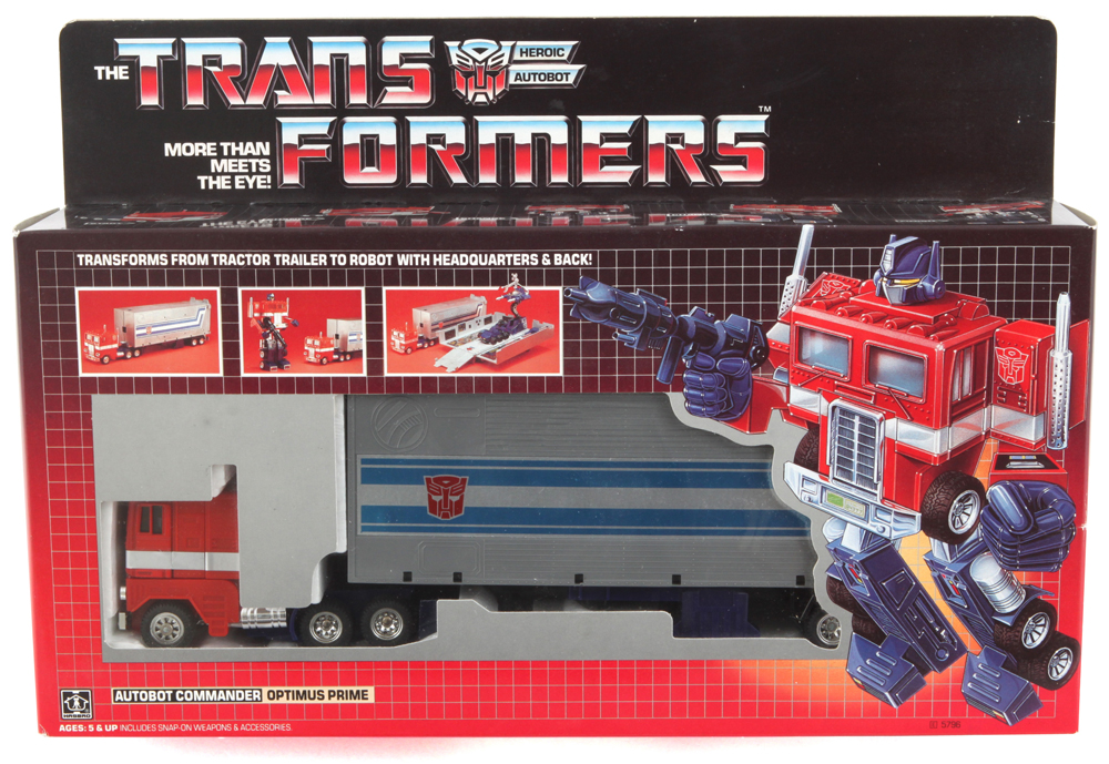 Optimus Prime, the leader of the Autobots in his toy packaging in red and white semi truck form, with a light grey trailer that has blue and white stripes with the red autobot logo. Pictured to the side, his robot form, where he has a blue head, hands and legs, and he's carrying his signature blaster rifle. The packaging is futuristic looking with the chrome logo at the top. It transforms from a dark to light red gradient and it has small pictures displaying his accessories.